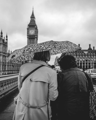 Rear view of people carrying umbrella while walking on street with big ben in background