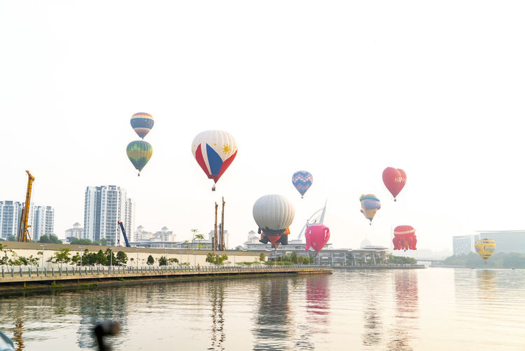 Hot air balloons in water against clear sky