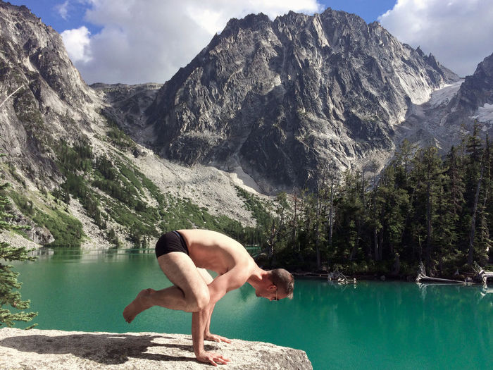 Side view of shirtless man practicing yoga on rock against dragontail peak