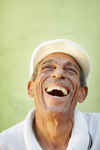 Senior man laughing against wall