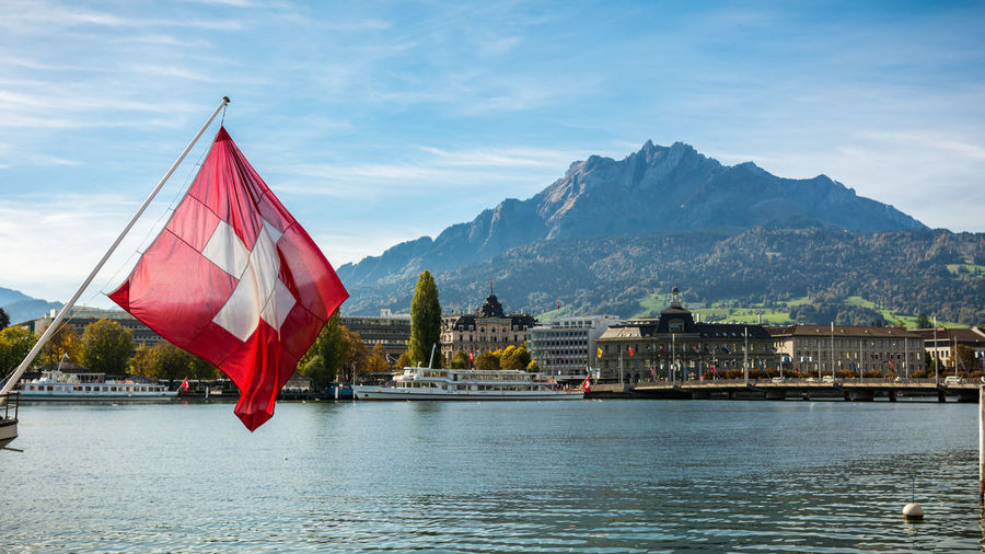 Swiss flag by lake against sky