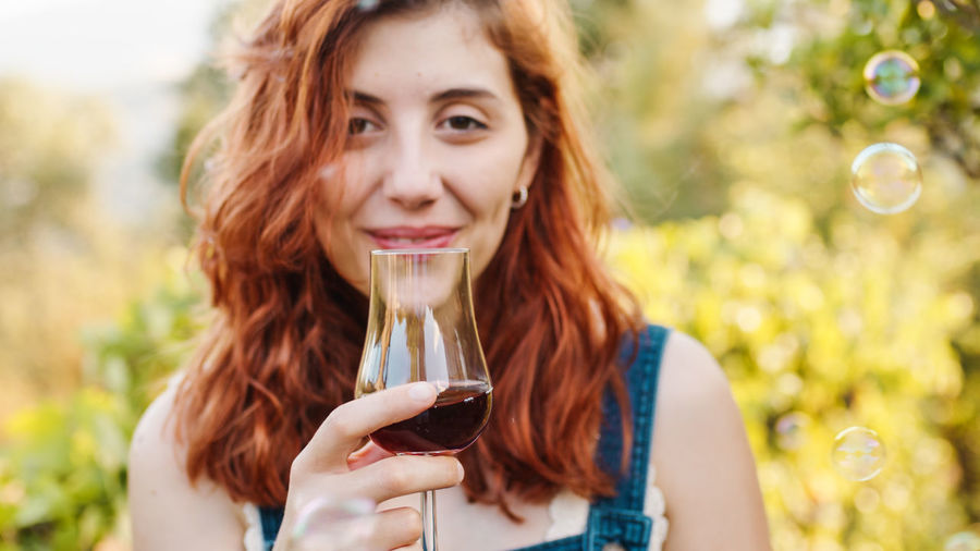 Woman with glass of red wine in the vineyard