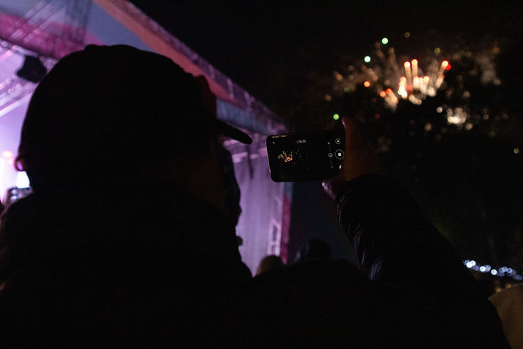 Portrait of silhouette man photographing illuminated smart phone at night
