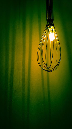 Illuminated wire whisk against wall in room