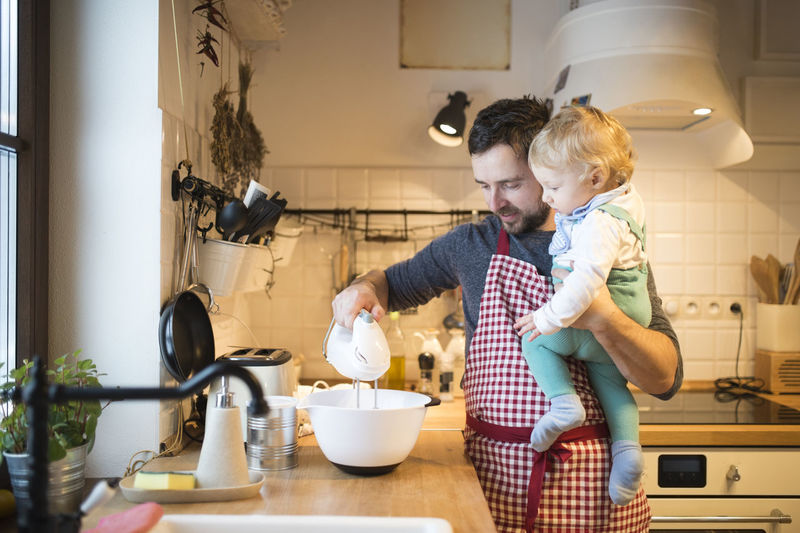 Father and baby boy in kitchen baking a cake