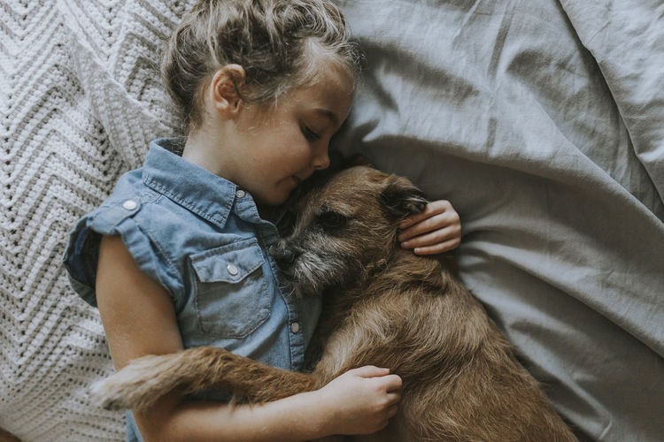 High angle view of girl sleeping with schnauzer on bed