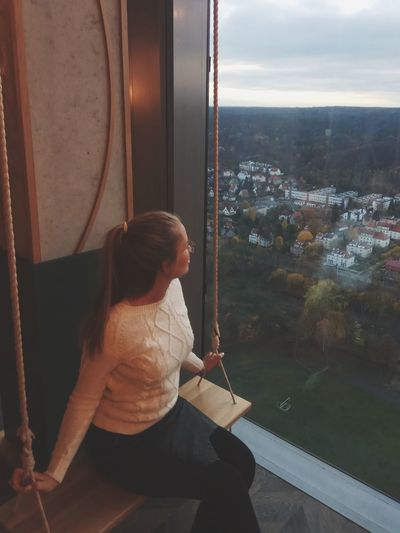 Woman looking through window sitting on swing