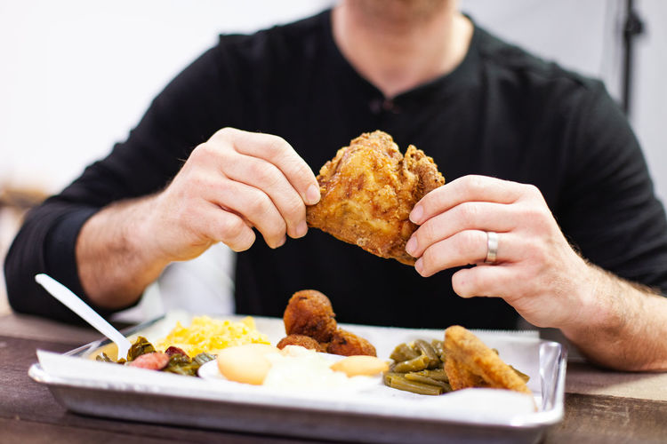 A man enjoys a fried chicken thigh at a buffet restaurant