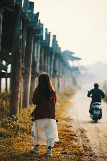 Rear view of woman walking on land against sky