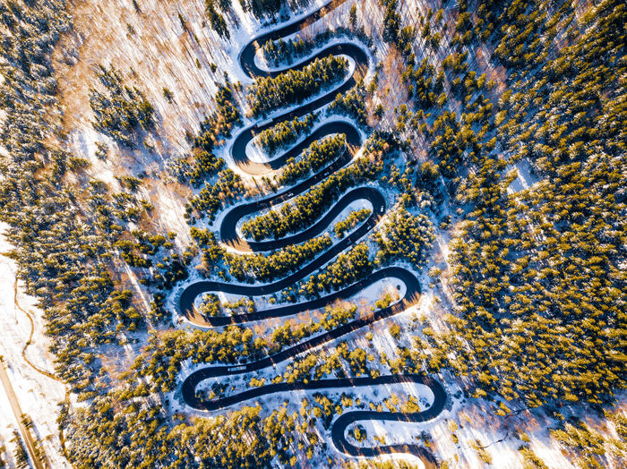 Aerial view of winding road amidst snow covered trees in forest