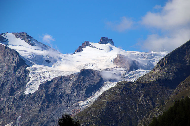 Scenic view of snowcapped gran paradiso massif and glaciers against sky, as seen from cogne in italy