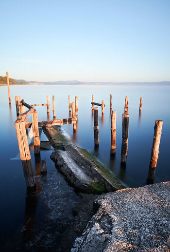 Long exposure of bolsena lake with water and old pier with poles