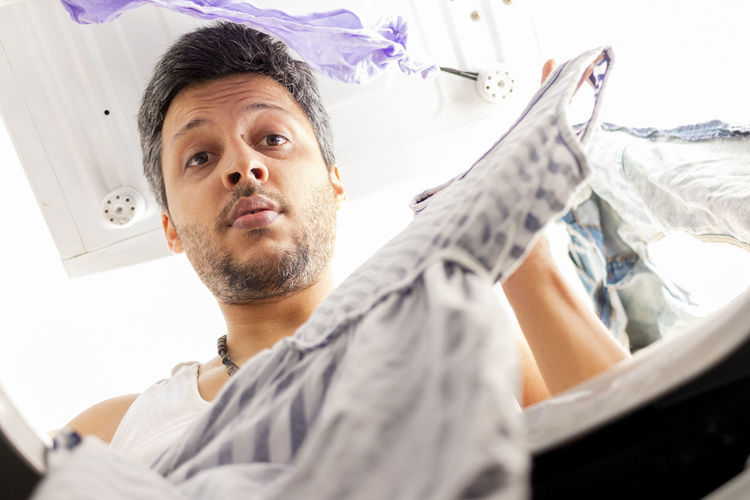 Low angle portrait of man holding dress in washing machine
