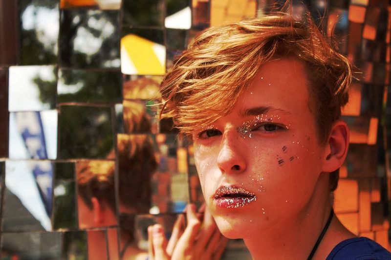 Close-up portrait of teenage boy with glitter on face