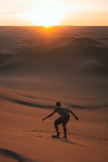 Rear view of man sandboarding at desert