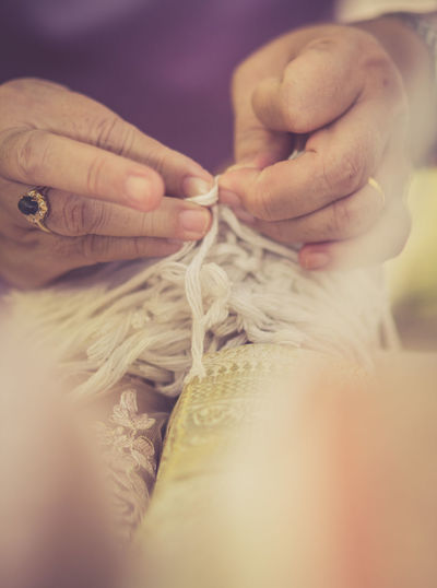 Cropped hands of woman tying bride wrist