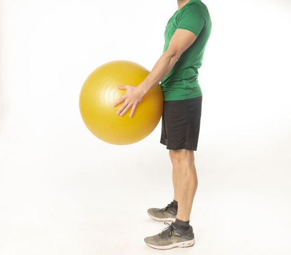 Man holding ball while standing against white background