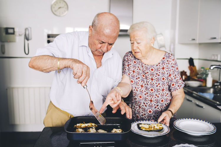 Senior couple serving stuffed eggplants in the kitchen