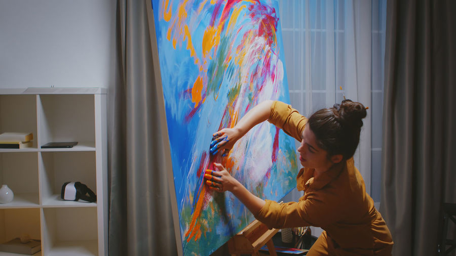 Side view of woman painting at home
