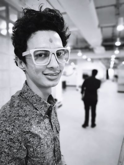 Portrait of smiling man in eyeglasses standing indoors