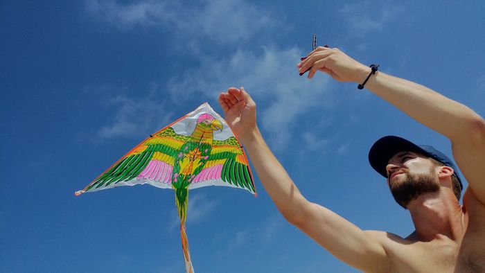 Low angle view of man holding kite against sky