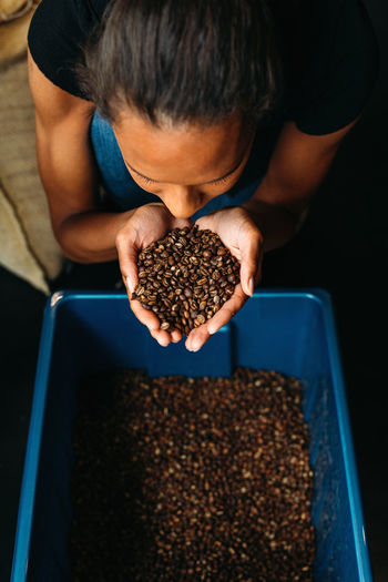 High angle view of woman smelling roasted coffee beans 