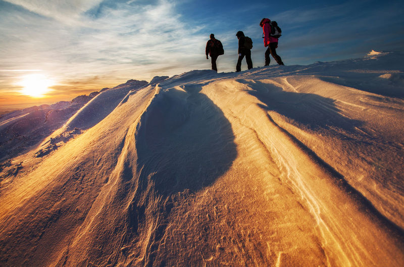 People walking on snow covered mountain against sky
