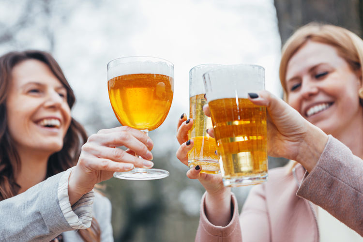 Friends toasting glasses on table against trees