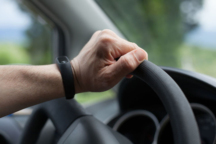 Close-up of man hand holding steering wheel in car