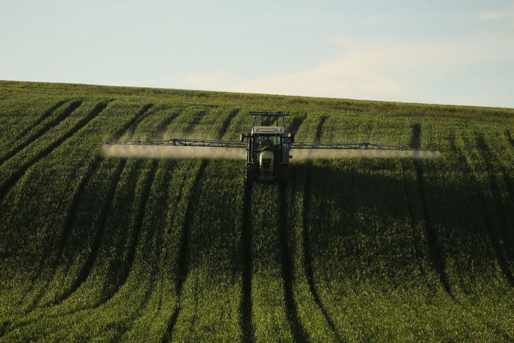 Scenic view of agricultural vehicle on field against sky