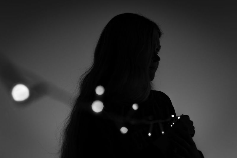 Low angle view of teenage girl holding illuminated light against clear sky