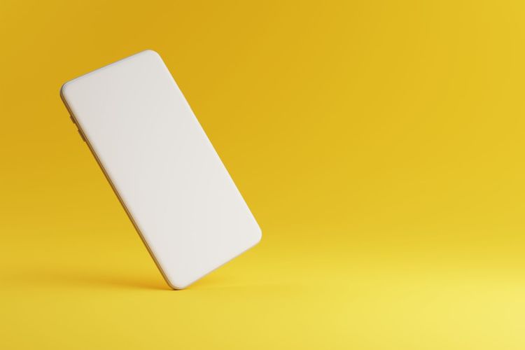 High angle view of smart phone on yellow background