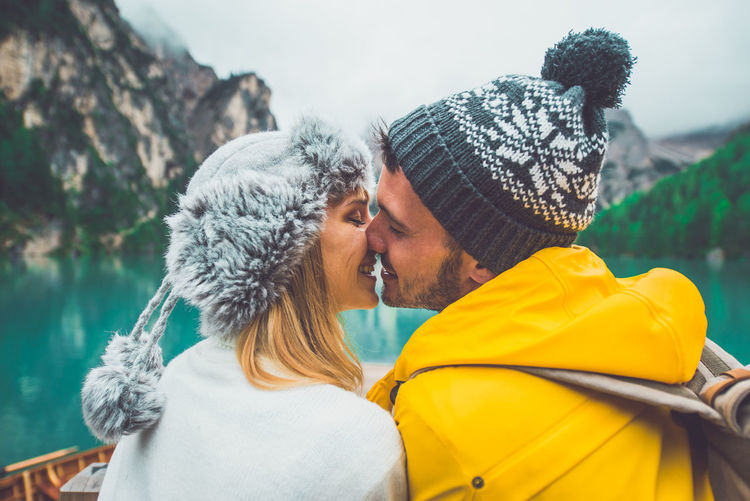 Close-up of couple kissing sitting in rowboat at lake during winter