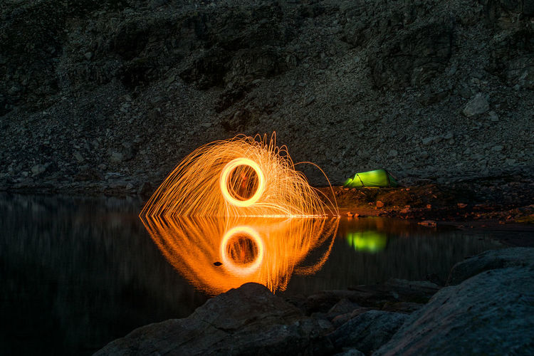 Reflection of burning wire wool on lake at dusk