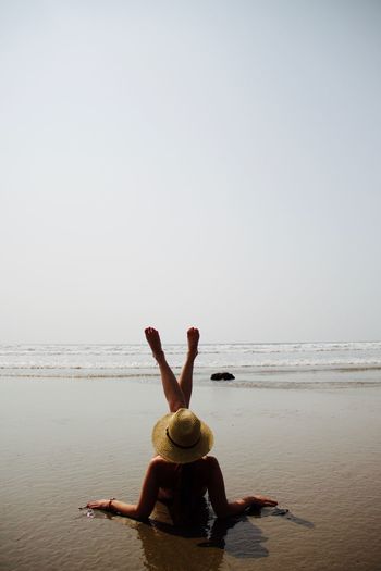Rear view of young woman enjoying at beach against clear sky