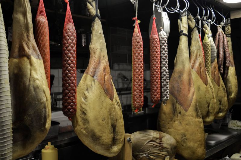 Prosciutto hams hanging in butcher shop