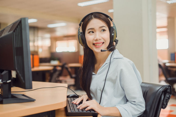 Smiling customer service representative talking on headset while working in office