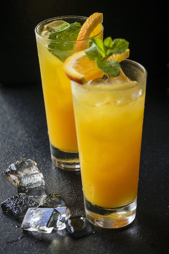 Two glasses of orange drink with ice cubes and mint leaves