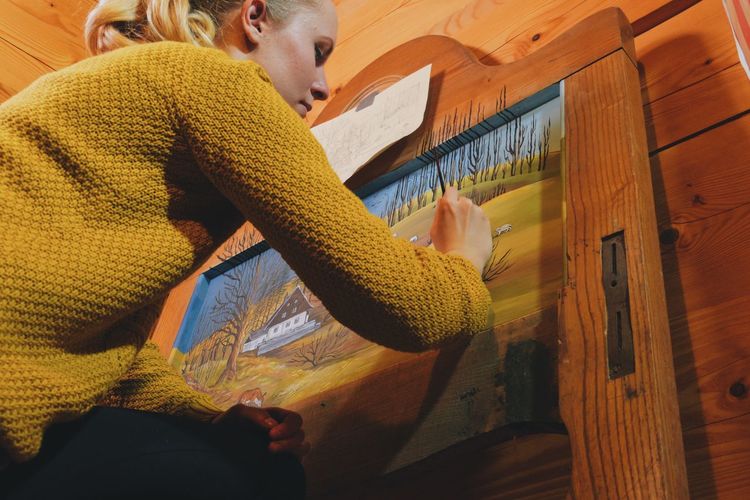 Low angle view of woman drawing on canvas in cottage