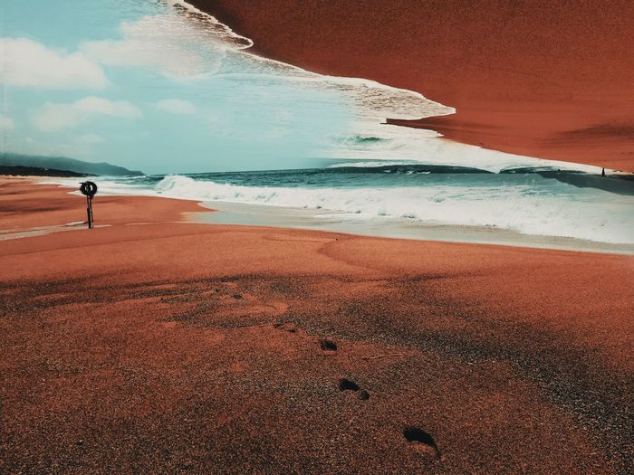 Surreal scenic view of beach by sea against sky