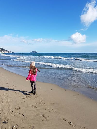 Girl walking at beach against sky