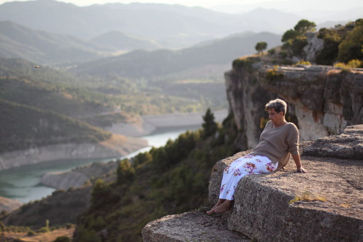 Woman sitting on rock looking at mountains