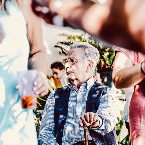 Senior man holding walking cane while sitting outdoors