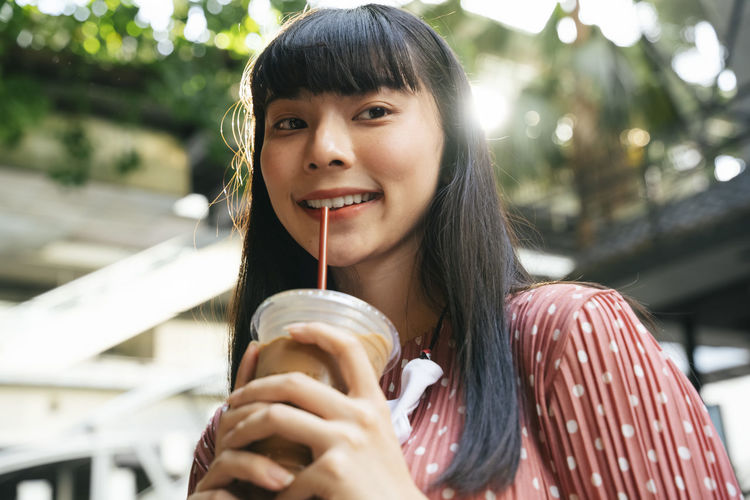 Portrait of smiling young woman holding drink