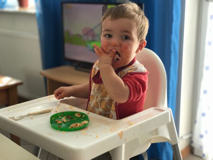 Close-up of boy having food on high chair at home