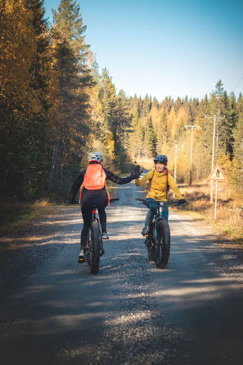 Cycling friends greet each other as they meet on a dirt road in vuokatti area, kainuu, finland.