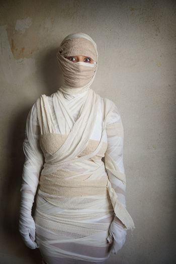 Portrait of woman wrapped with bandages against wall