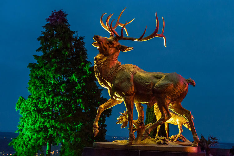 Low angle view of deer statue against sky at dusk