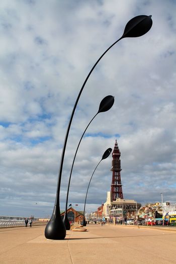 Decoration on promenade with blackpool tower against cloudy sky