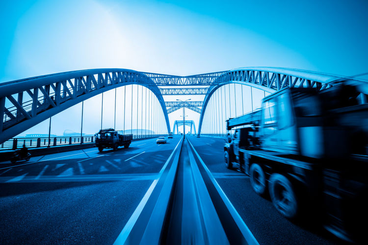 Vehicles on bridge against clear blue sky